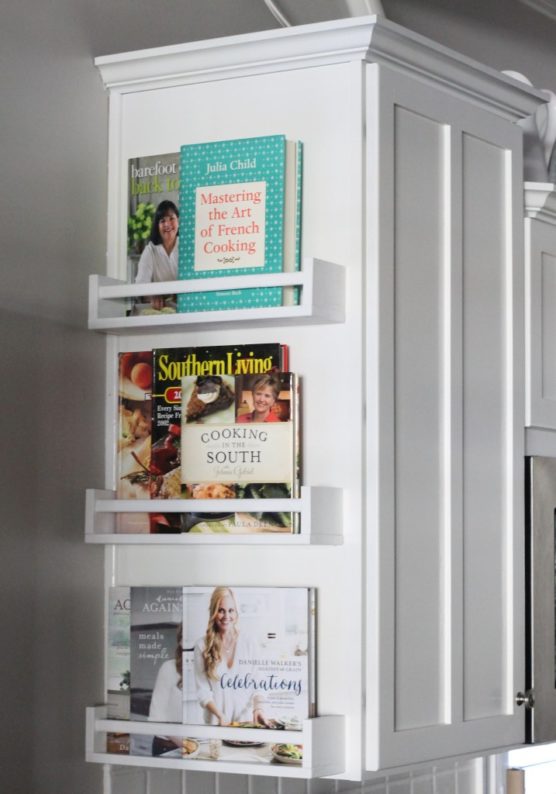 Cookbooks stored in spice shelves attached to cabinet