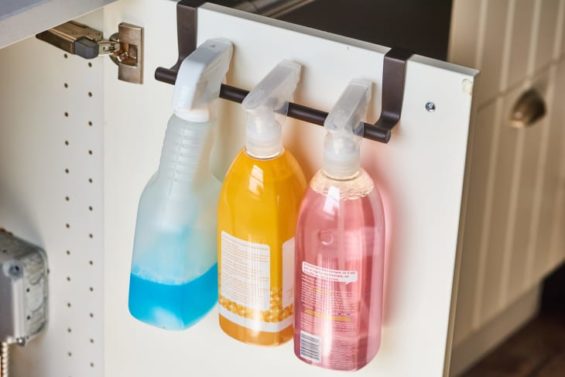 Hanging cleaning sprays on a towel bar attached to a cabinet door