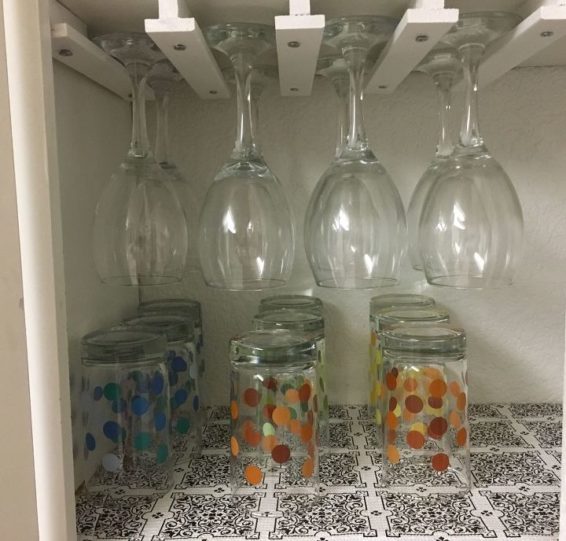 Wine glasses hanging upside down on T-shaped moldings inside a cabinet